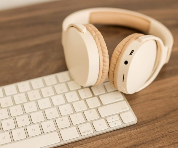 Close Up Of Headphones And Keyboard Arranged On Wooden Table